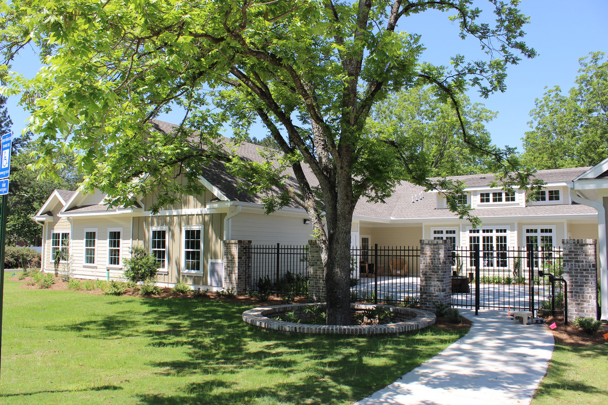 Residential home with a covered porch and mature pecan tree on the grounds at The Orchard at Stone Creek, Hahira GA